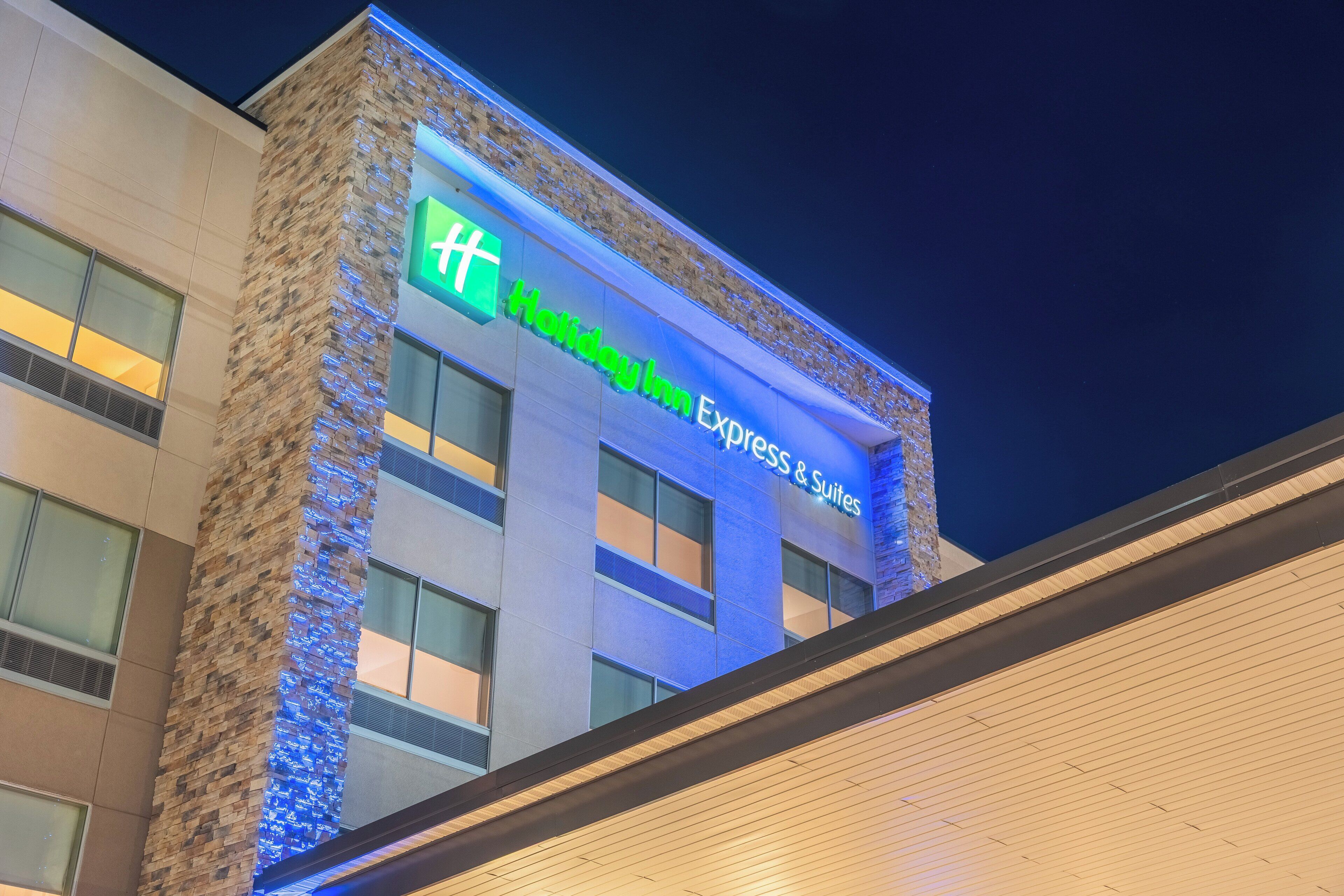 A Holiday Inn Express & Suites building with a prominent sign and a brick facade.