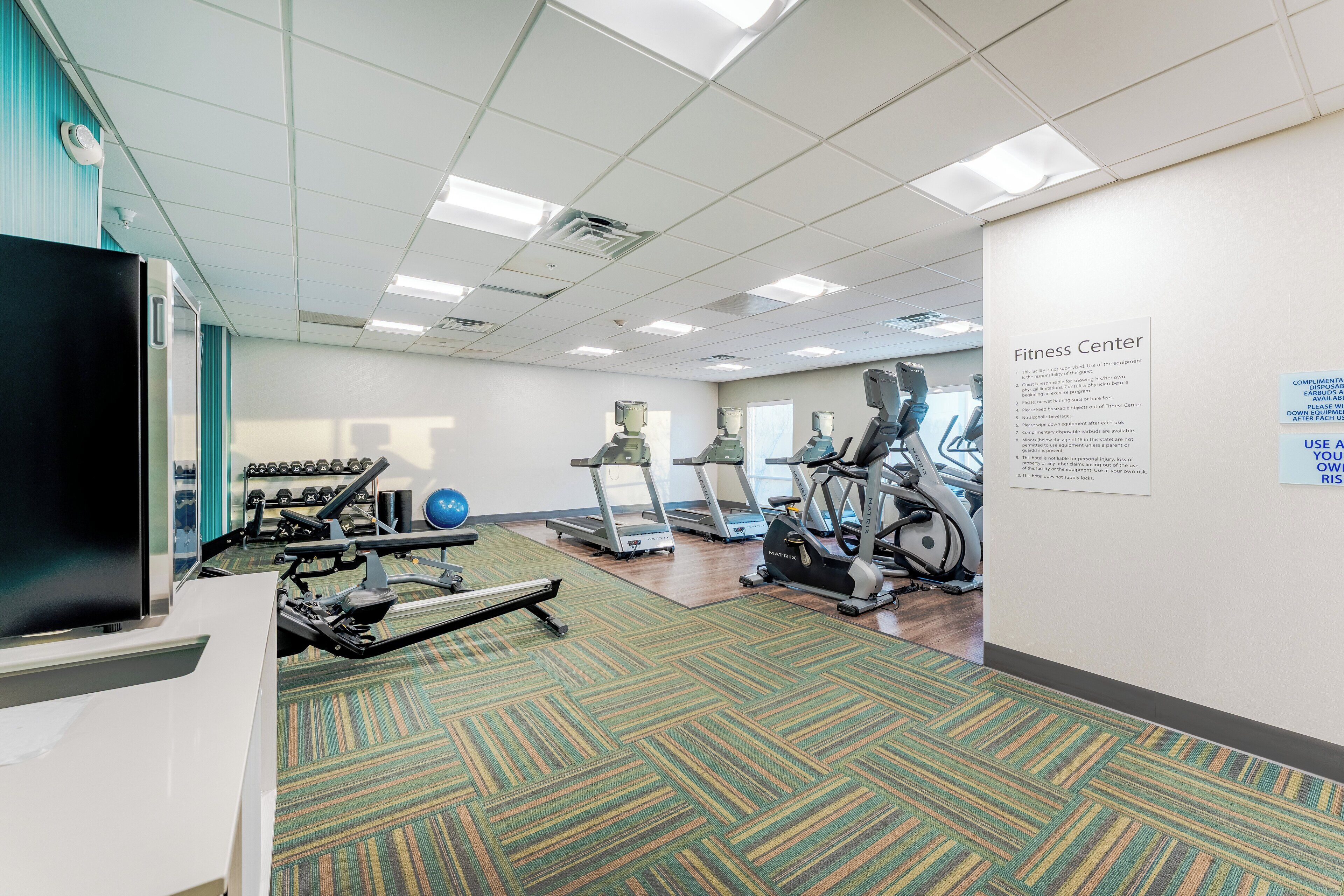 A fitness center with treadmills, elliptical machines, and free weights.
