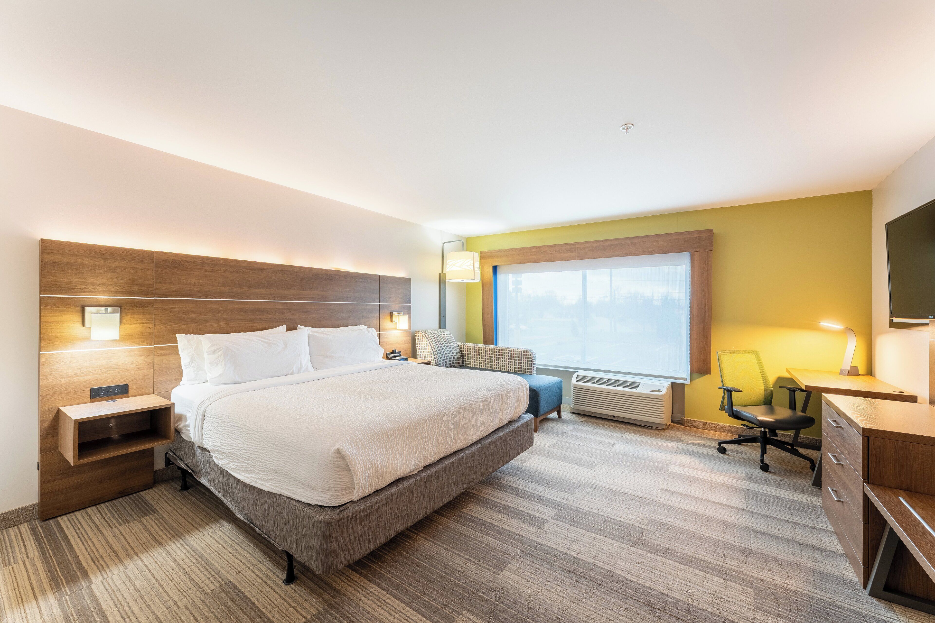 Una habitación de hotel moderna con una cama grande, mesitas de noche, un escritorio y una silla.