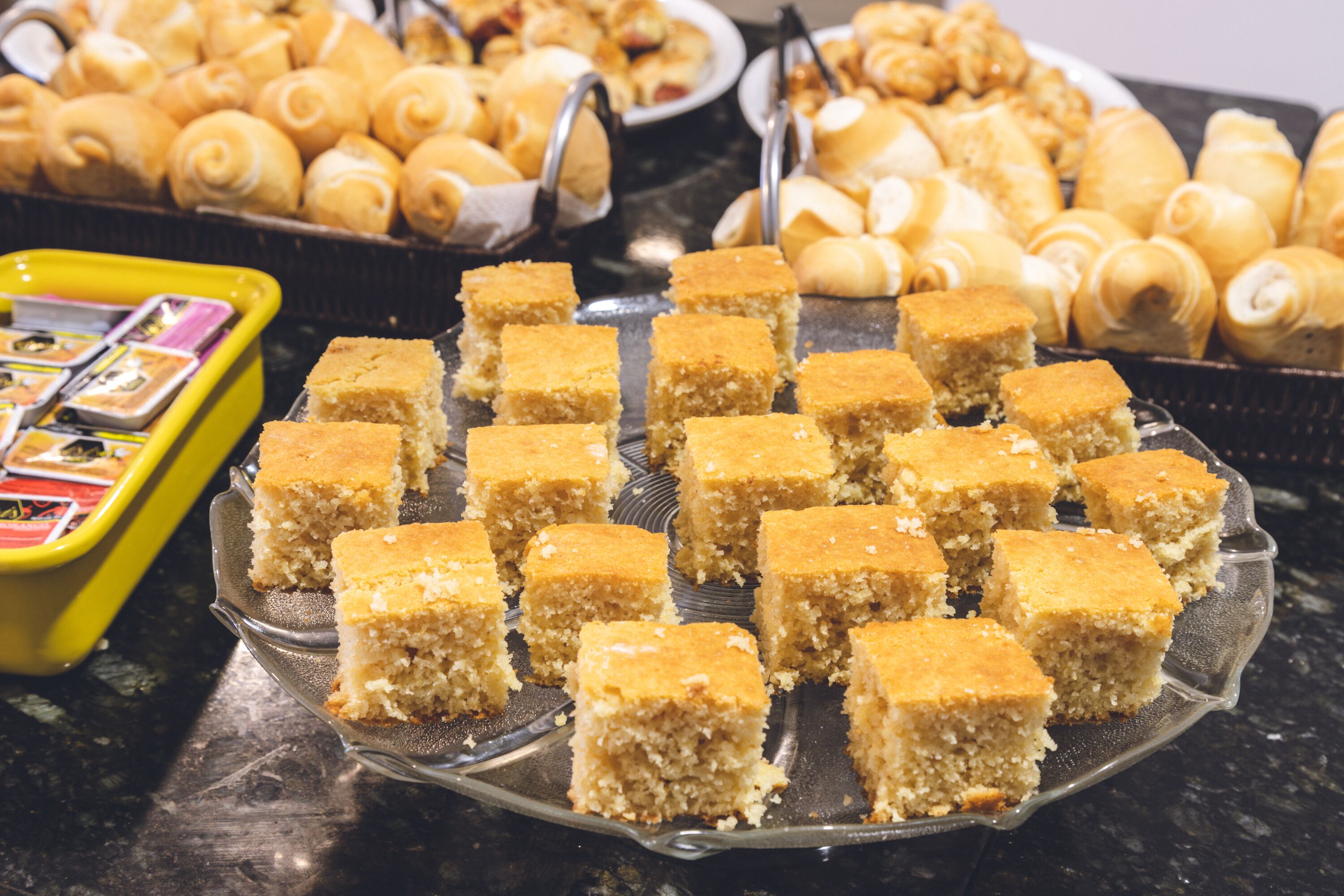 A buffet table with various baked goods including pastries and cornbread squares.