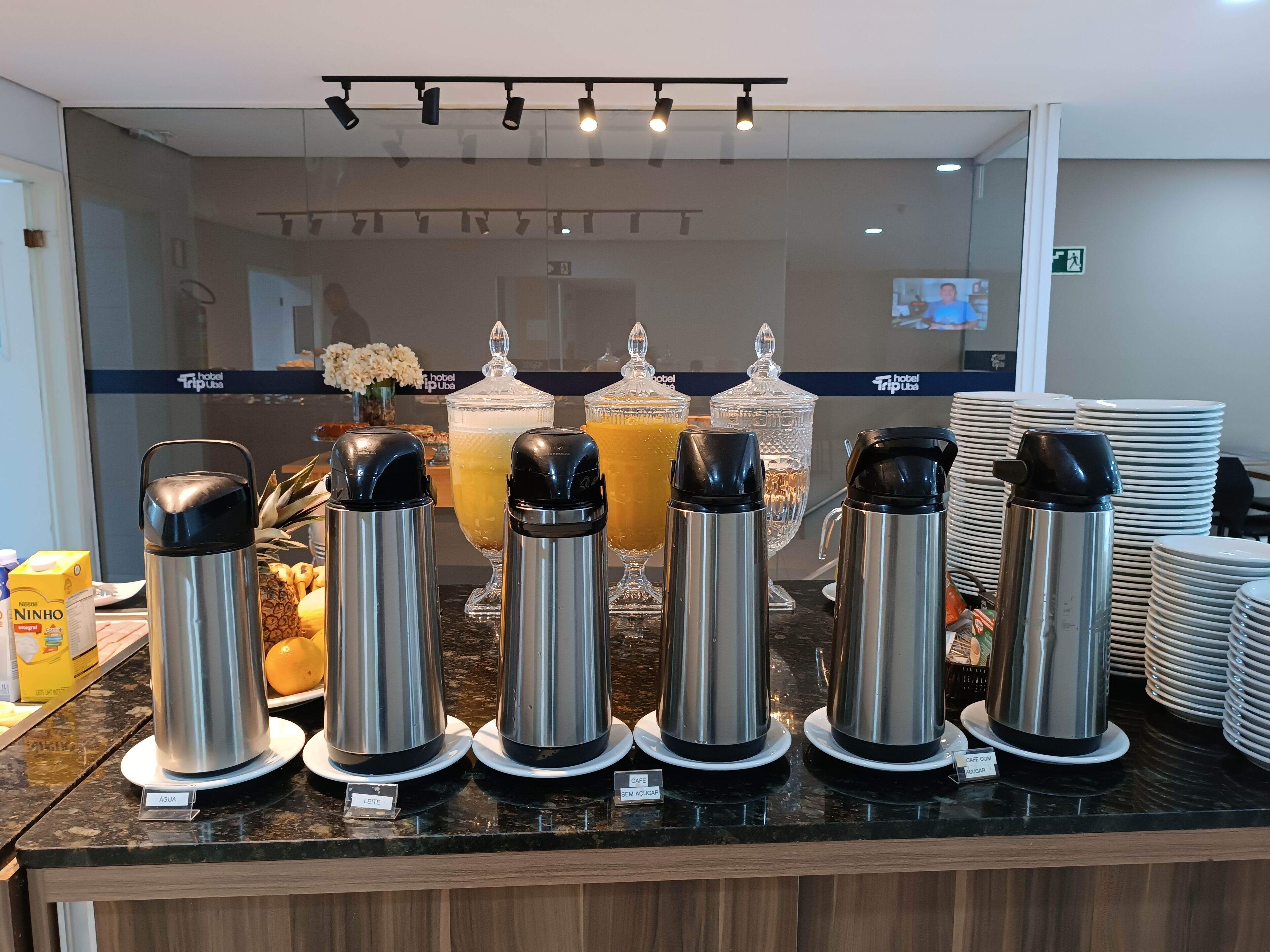 Un bufé de desayuno con varios dispensadores de bebidas etiquetados para agua, leche y jugo.