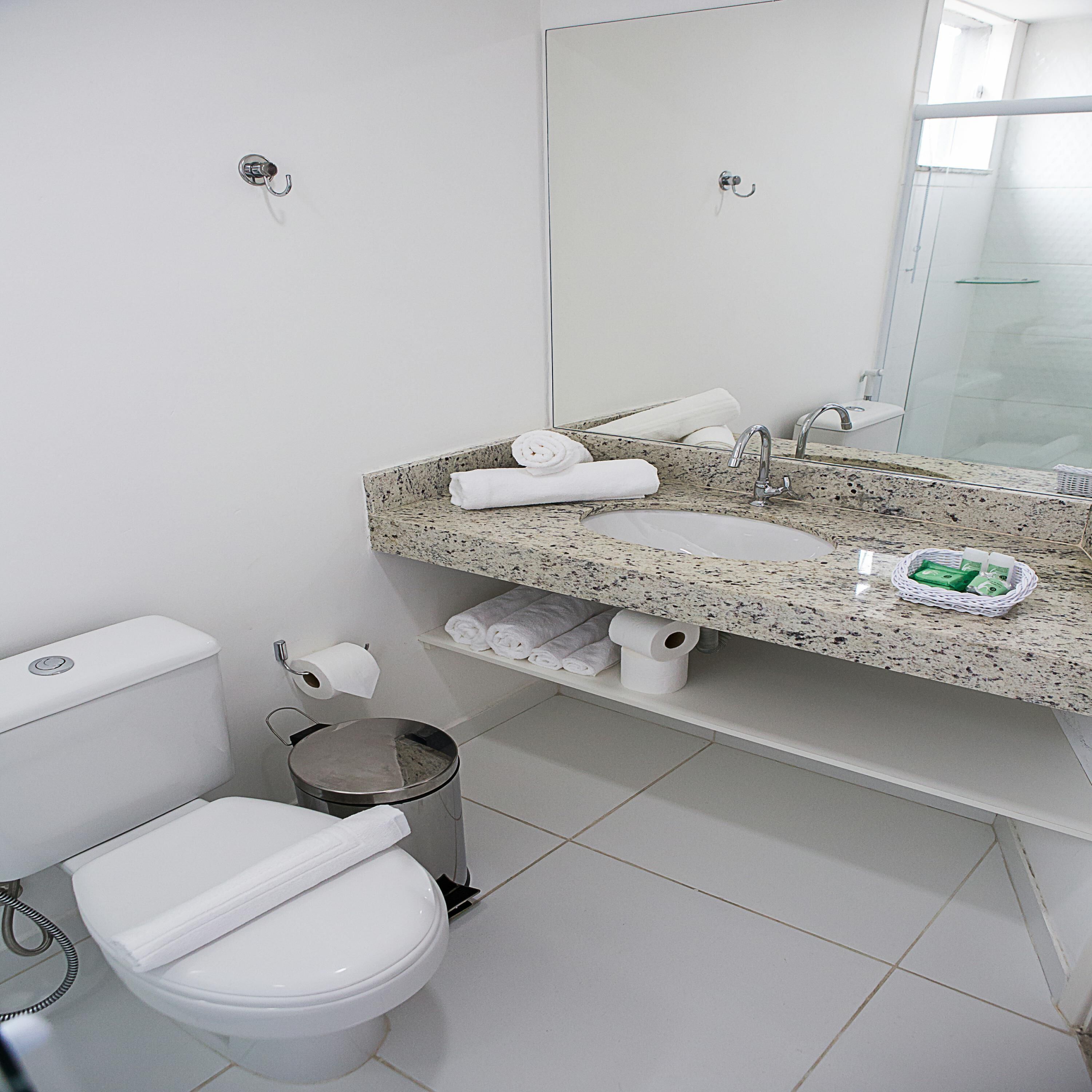A modern bathroom with a white toilet, a granite sink, and a glass shower enclosure.