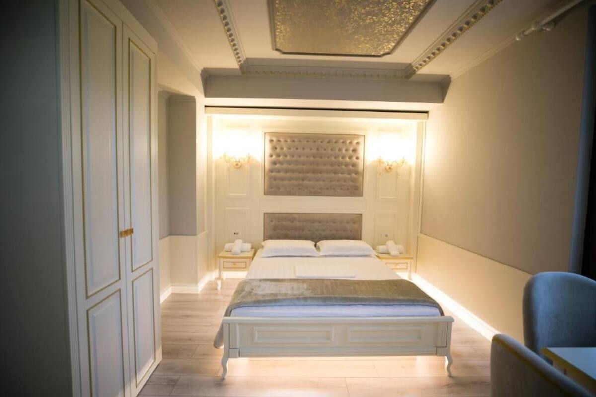 A bedroom with a large bed, two bedside tables, and a chandelier.