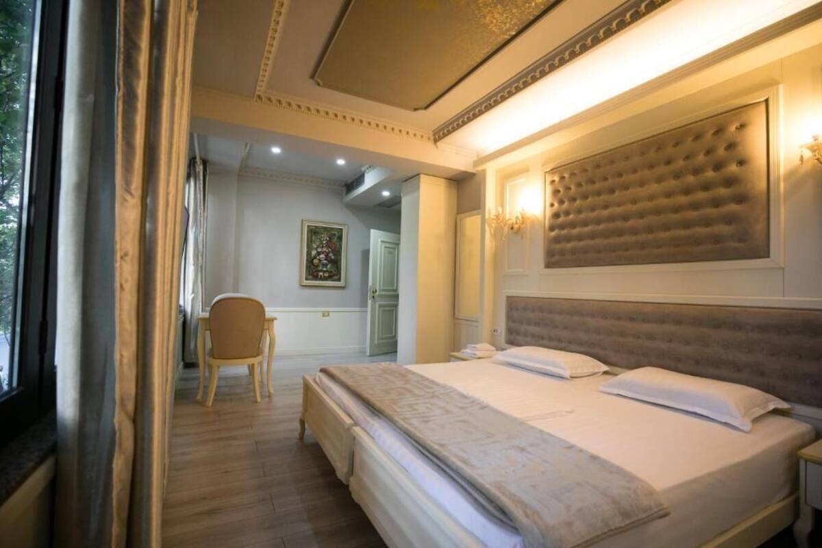 A bedroom with a large bed, a chair, and a painting on the wall.
