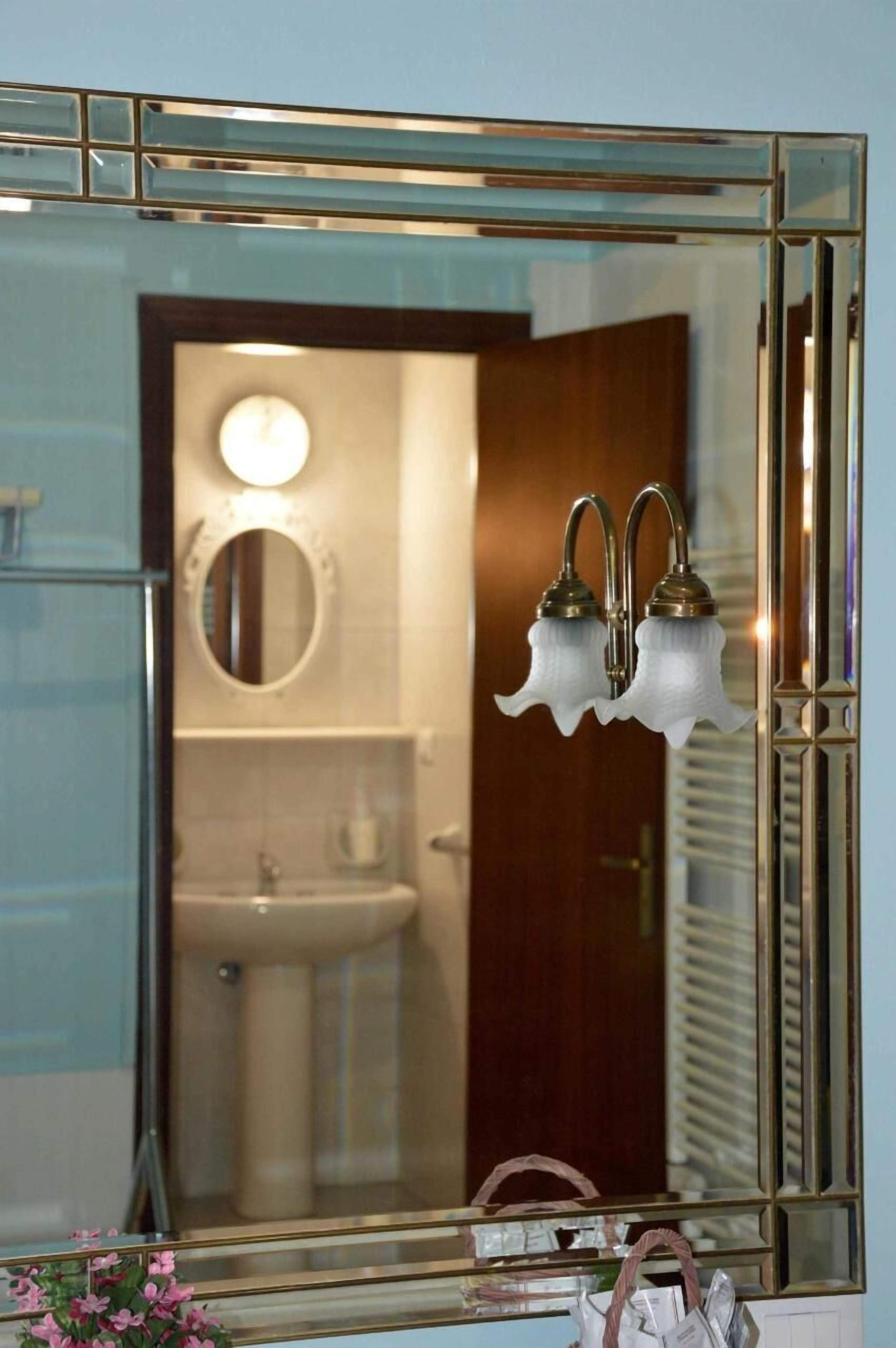 A bathroom with a large mirror, a sink, and two wall-mounted light fixtures.