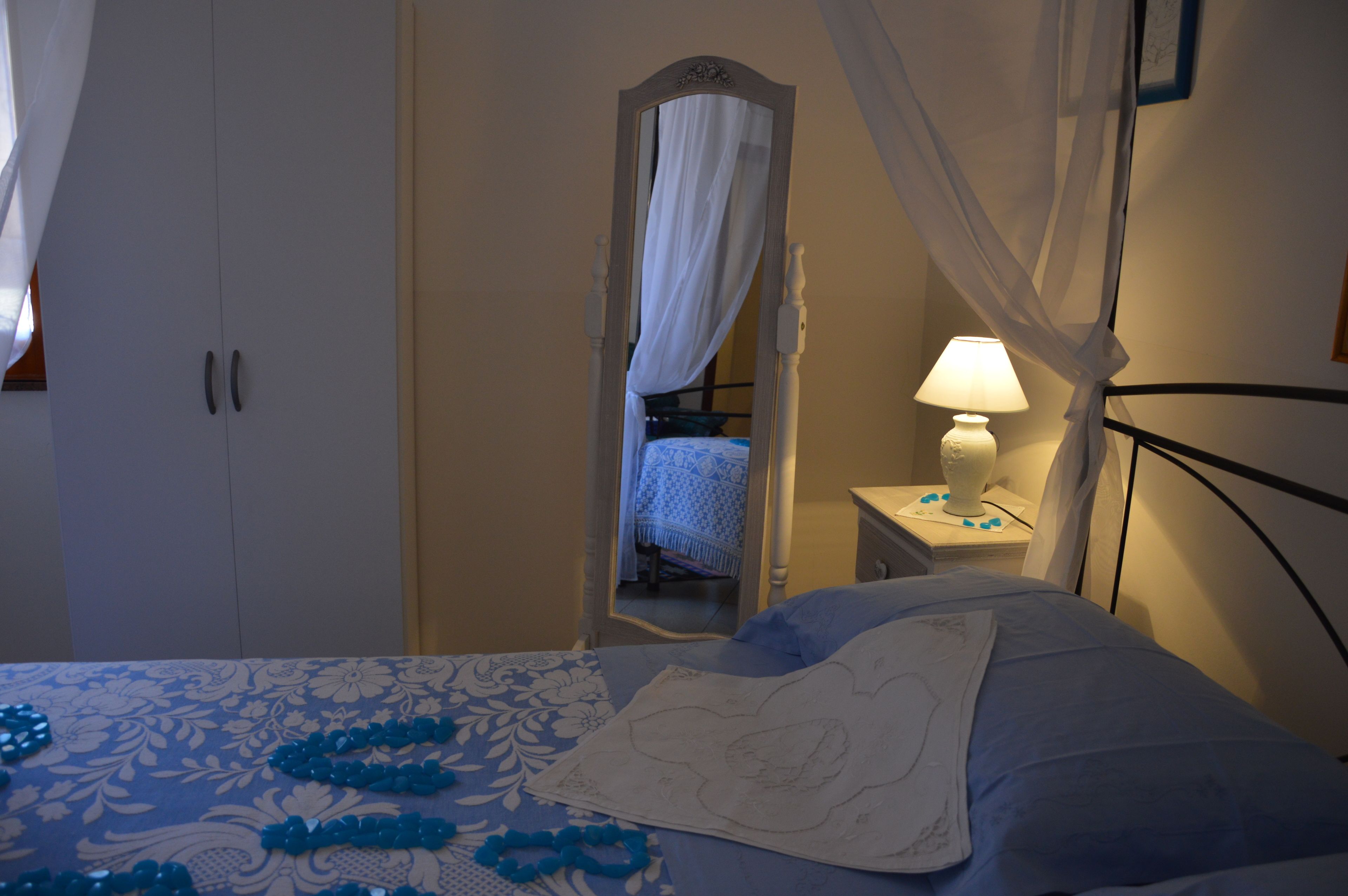 A bedroom with a bed, a nightstand, a mirror, and a wardrobe.