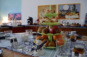 A dining table with a tiered fruit stand, a snowman figurine, and various kitchen items.