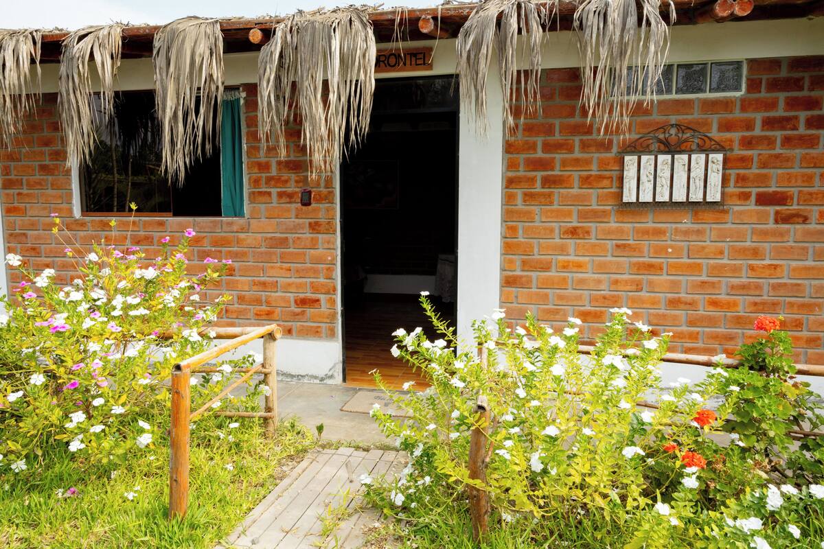 Un edificio rústico de ladrillo con entrada de madera y techo de paja a dos aguas.