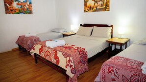 Quarto de hotel com duas camas, piso de madeira e duas pinturas nas paredes.
