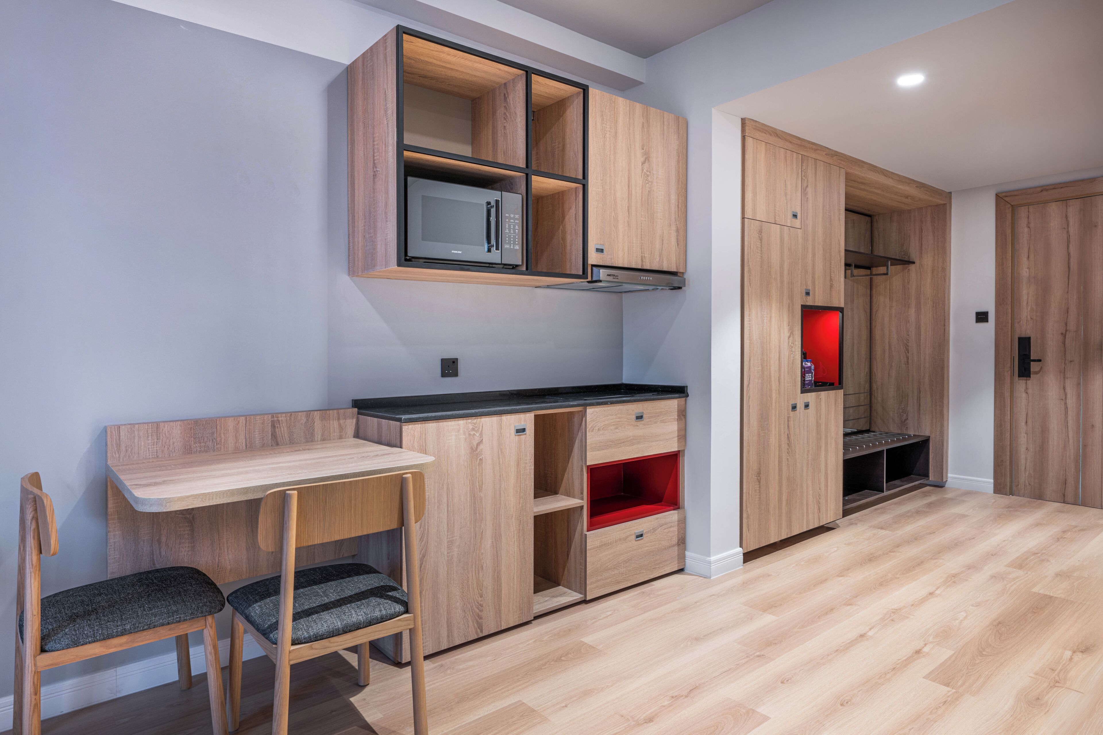 Una cocina moderna con electrodomésticos integrados, un comedor de madera y una pared decorativa roja.
