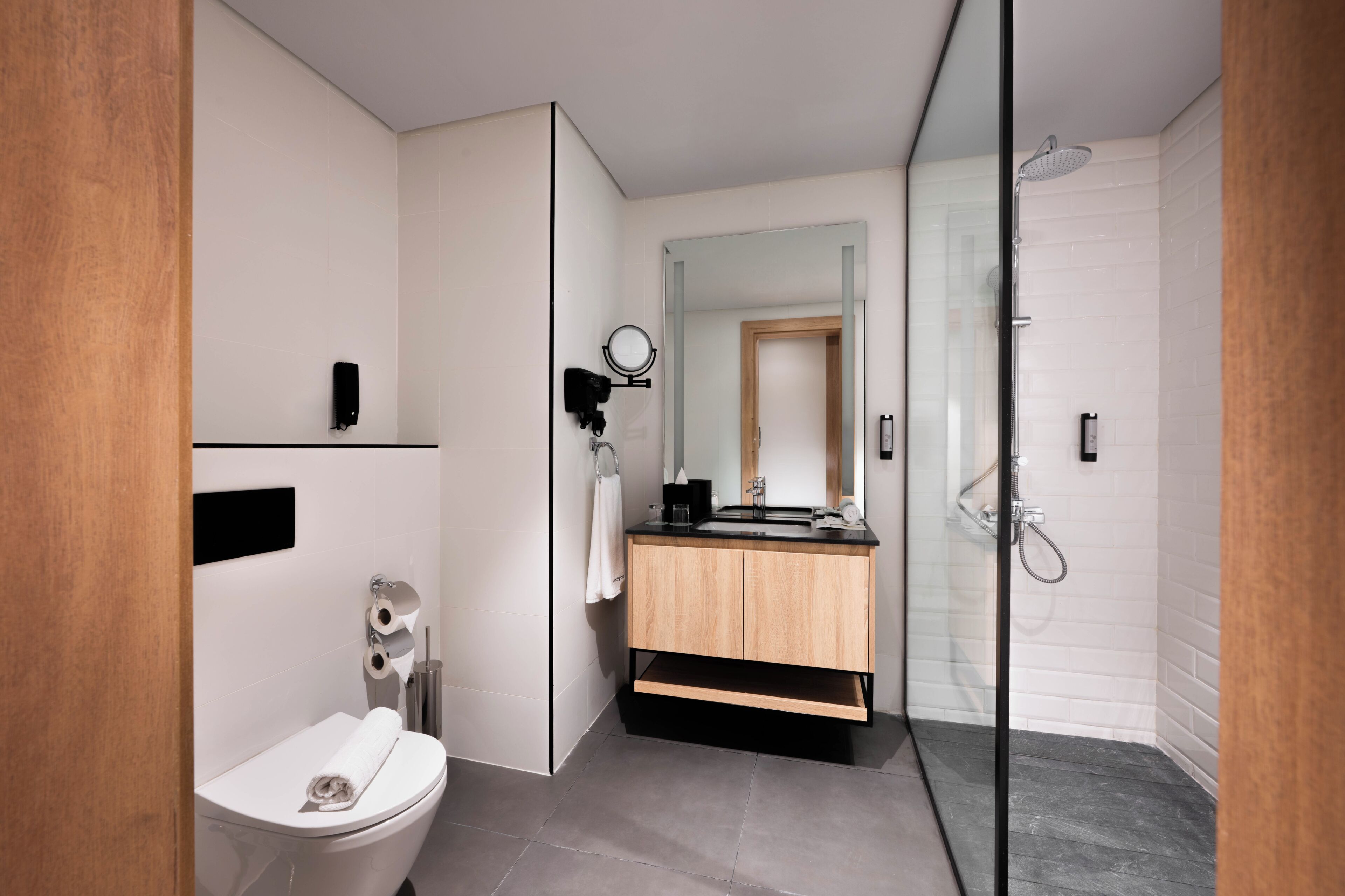 A modern bathroom with a toilet, sink, mirror, and shower.