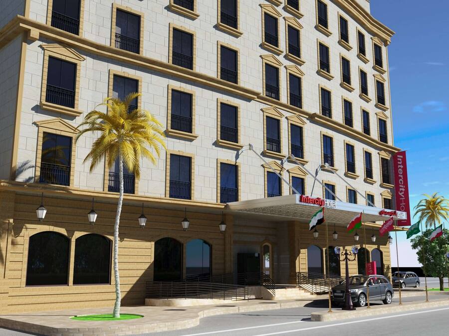 Et hotel med flere etager, en symmetrisk facade, store vinduer og en central indgang med trappe.