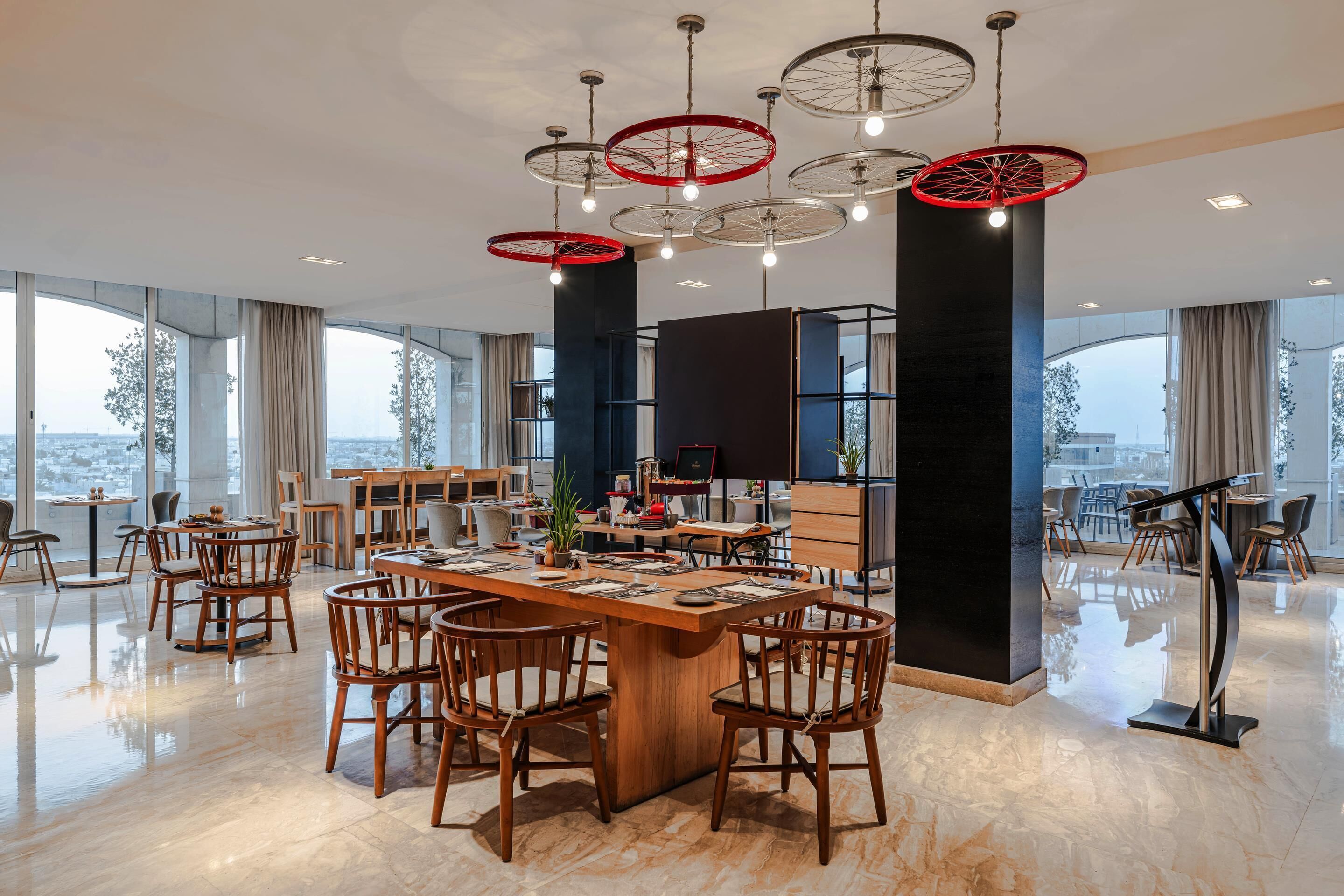 Un comedor espacioso con una gran mesa de madera, múltiples sillas y un diseño de techo moderno con lámparas colgantes.