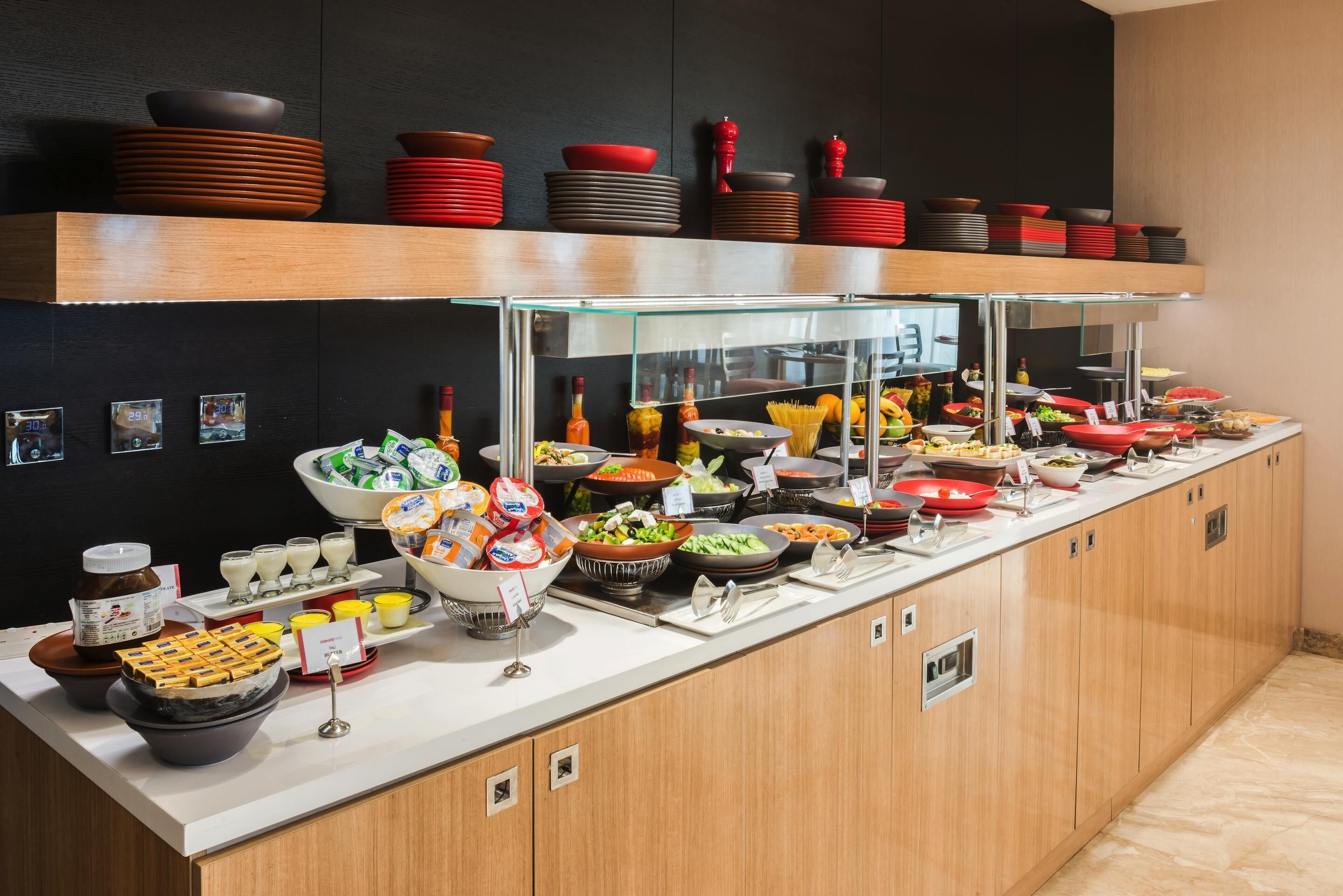 A buffet with various food items and condiments, a glass display case, and a wooden counter.