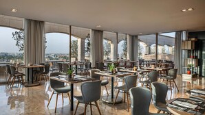 A modern restaurant with high ceilings, large windows, and a city view. - IntercityHotel Riyadh Malaz (Riyadh)