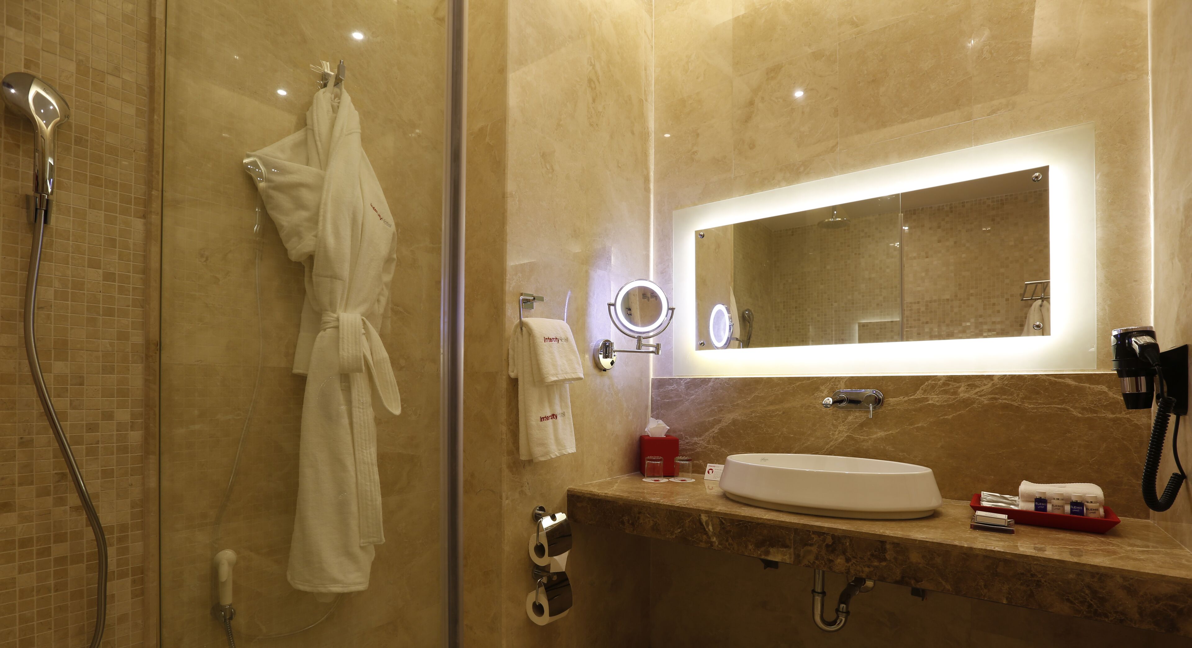Un baño moderno con ducha de vidrio, tocador con lavamanos y un espejo grande.