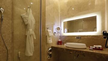 Un baño moderno con ducha de vidrio, tocador con lavamanos y un espejo grande.