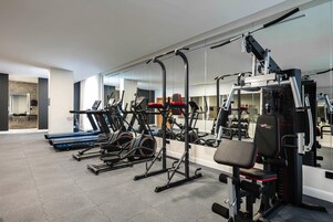 Ein Fitnessstudio mit Laufbändern, Kraftgeräten und einer Trainingsbank.