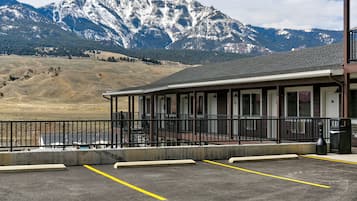 A building with a balcony overlooking a parking area, with mountains in the background.