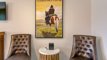 Una habitación con dos sillones de cuero, una pequeña mesita de madera y un cuadro enmarcado de un vaquero a caballo.
