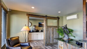 A modern kitchen with white cabinets, a coffee maker, and a large window with blinds. - The Roosevelt Hotel - Yellowstone (Gardiner)
