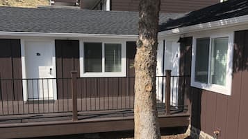 A mobile home with a porch, a tree, and a stone wall.