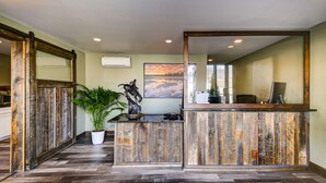 A reception area with a rustic wooden desk, a large mirror, and a potted plant. - The Roosevelt Hotel - Yellowstone (Gardiner)