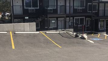 En byggnad med flera våningar och ett platt tak, en parkeringsplats med markerade parkeringsrutor och en brandpost.