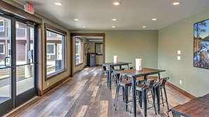 A spacious indoor area with large windows, wooden flooring, and a dining setup with tables and chairs. - The Roosevelt Hotel - Yellowstone (Gardiner)