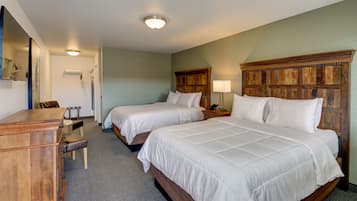 A hotel room with two beds, a wooden dresser, a desk, and a chair.