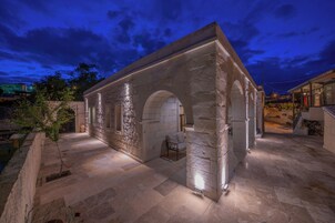 Un edificio de piedra con arcos y suelo de baldosas, iluminado con luz artificial.