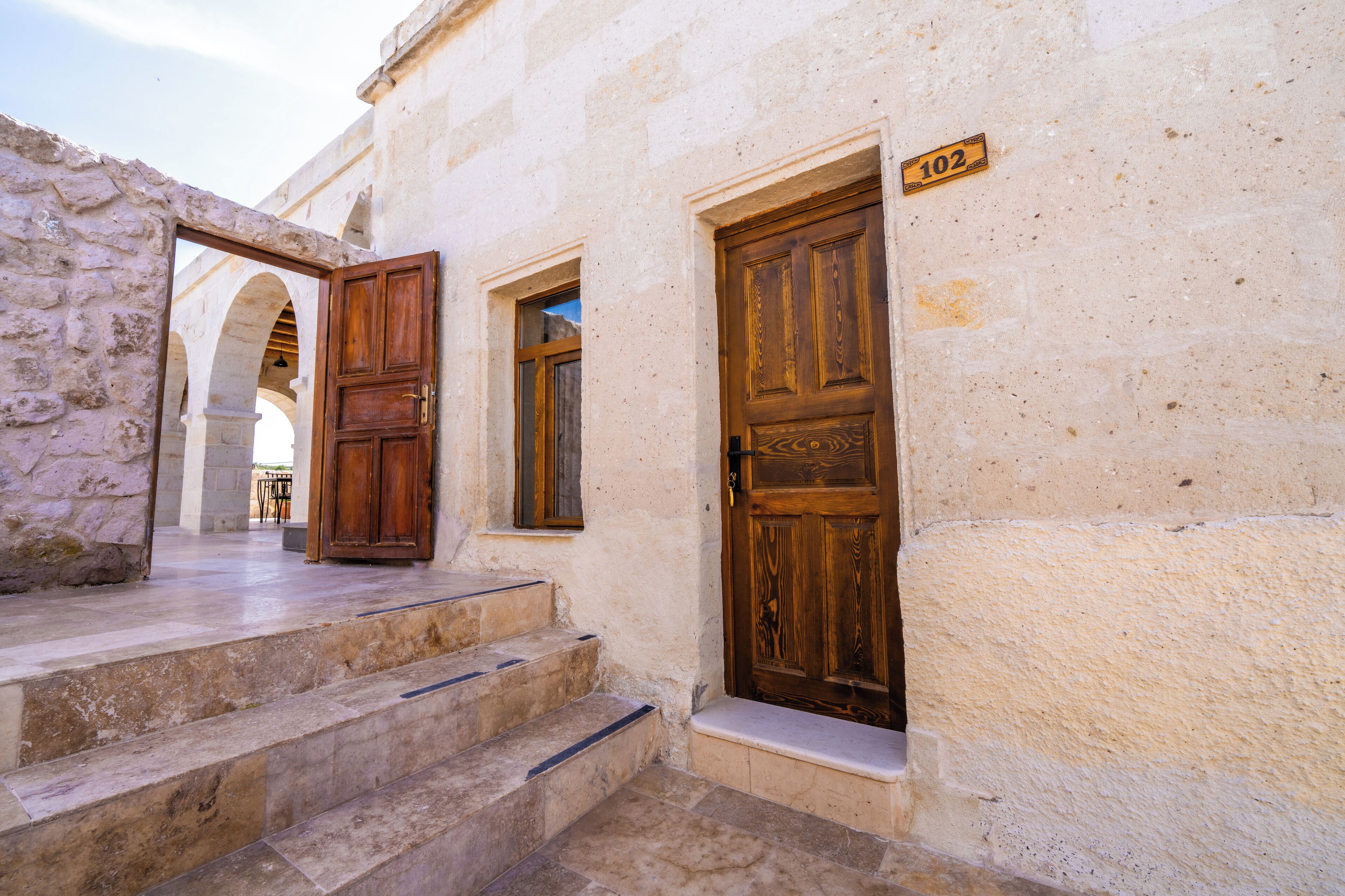 A building with stone walls, wooden doors, and a number plaque.