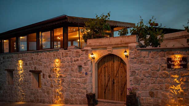 A stone building with a wooden door and a sign for "Hotel Asgard Suites." - Asyada Suites Hotel (Ürgüp)