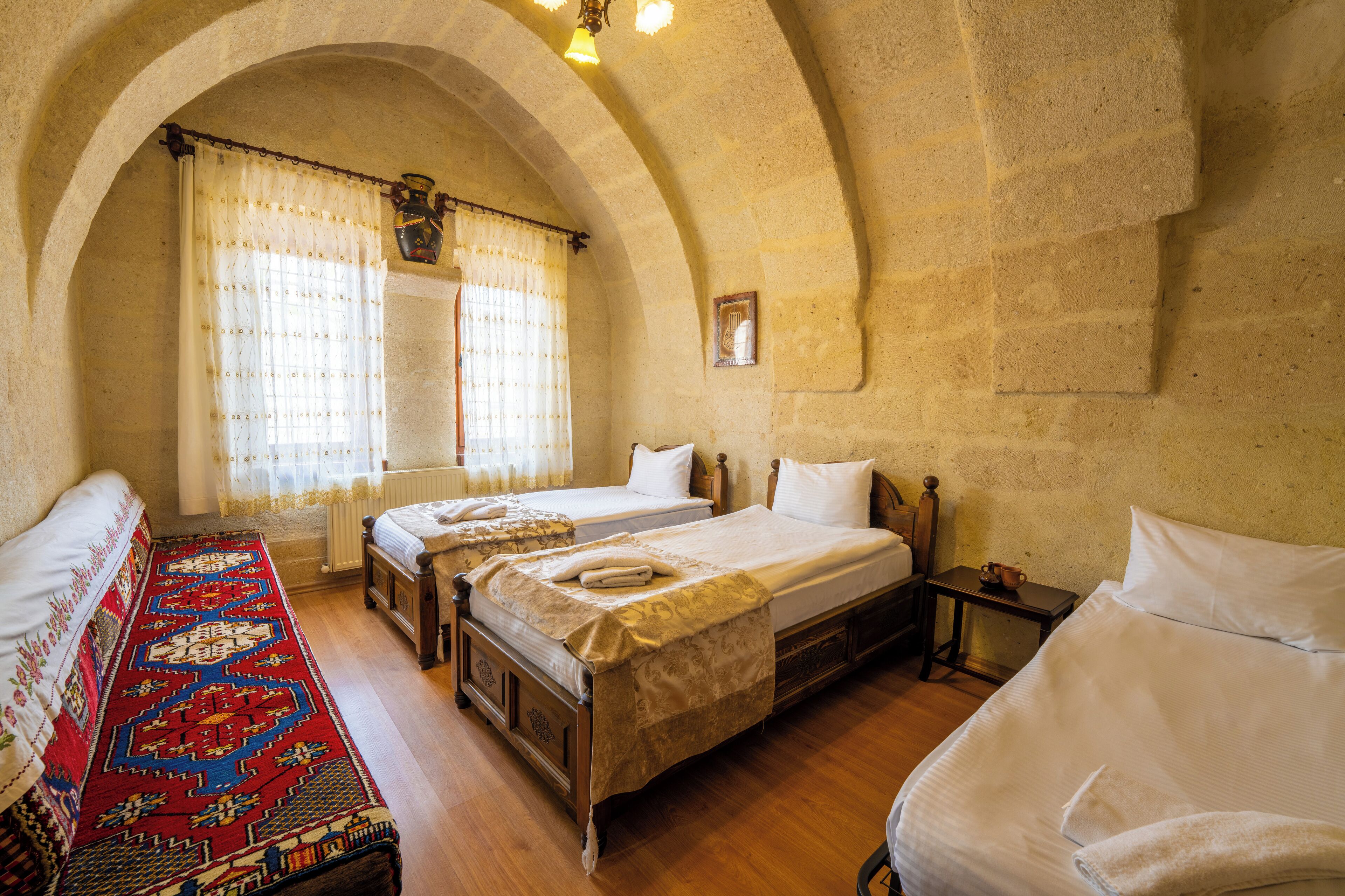 A traditional room with two beds, a patterned rug, and a stone wall.