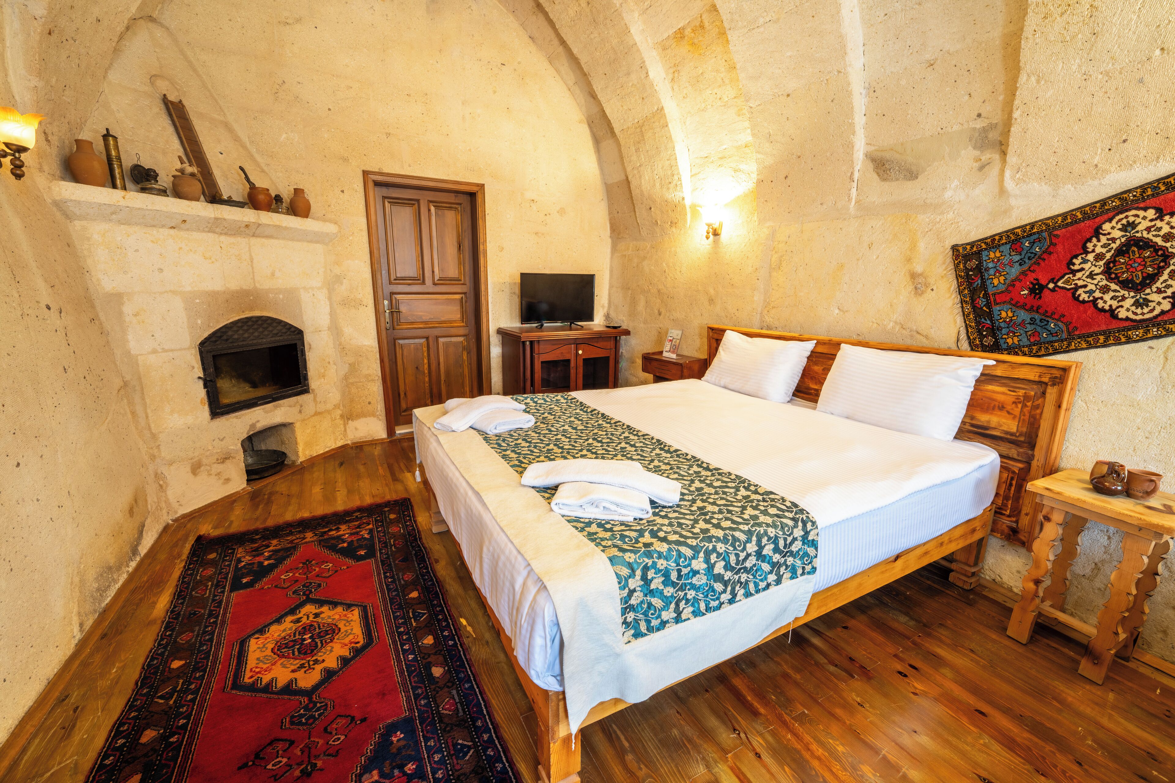 Un dormitorio con cama, chimenea, televisión y una alfombra decorativa.