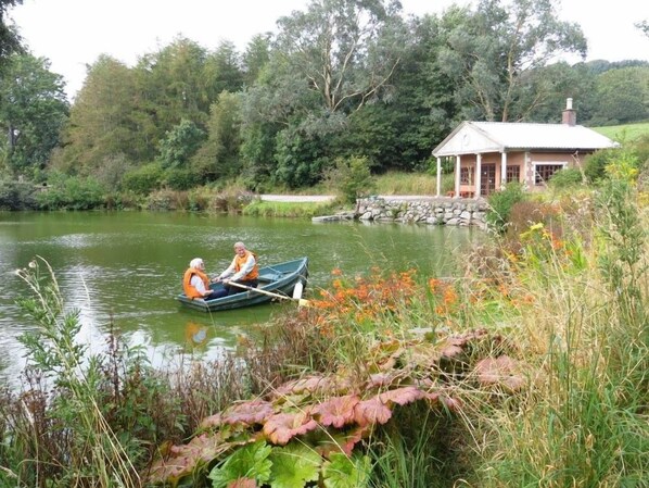 Une scène paisible au bord d’un lac, avec une petite barque et deux personnes portant des gilets de sauvetage orange.