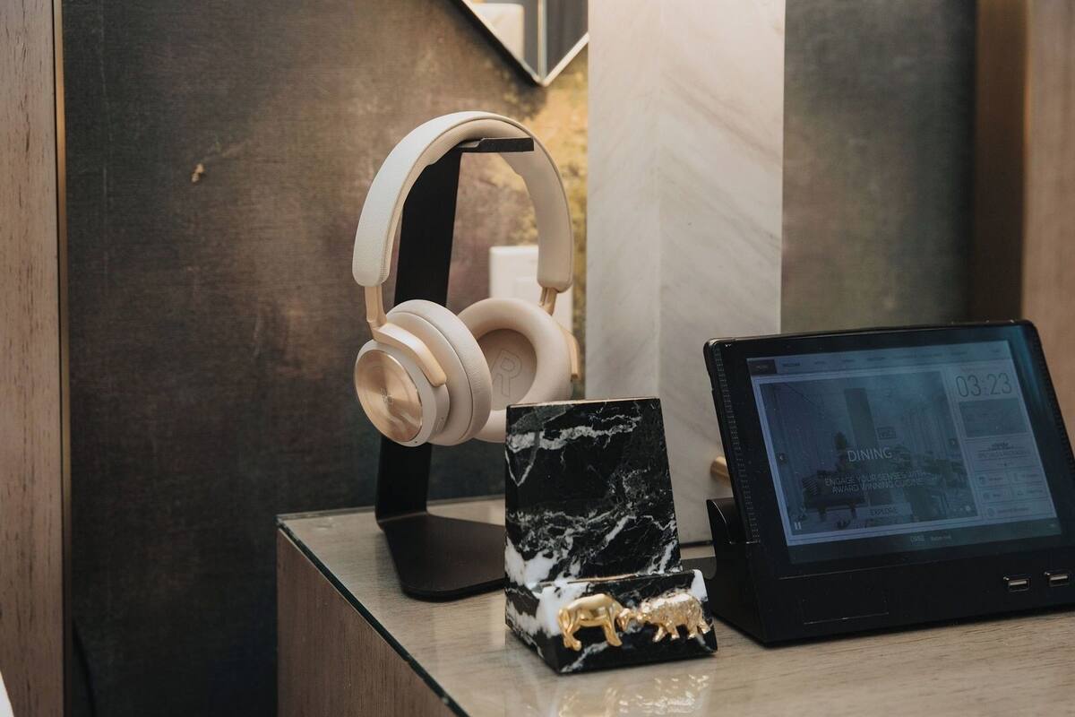 A modern room with a marble accent piece, a tablet displaying a dining menu, and a pair of headphones on a stand.