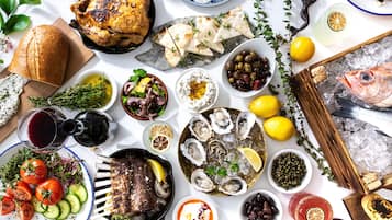 Diversos alimentos, como pollo a la parrilla, mariscos y verduras, dispuestos sobre una mesa.