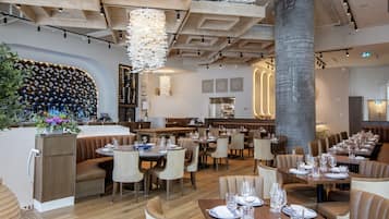 Un restaurante moderno con vigas de madera, un pilar grande y diferentes opciones de asientos, como cabinas y mesas.