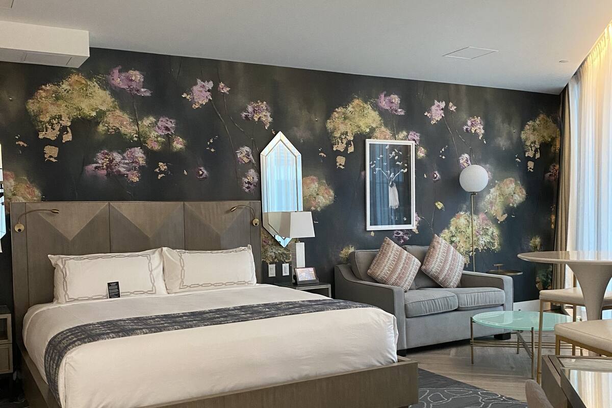 A modern bedroom with a large bed, a gray sofa, and a small table.
