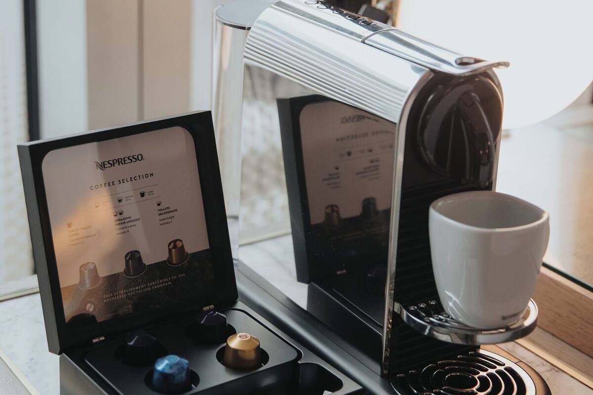 A Nespresso coffee machine with a cup and a coffee pod holder on a marble countertop.