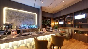A modern bar area with a marble countertop, bar stools, and a variety of bottles and glasses. - EXchange Hotel Vancouver (Vancouver)