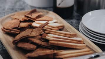 A wooden tray with snacks and a bottle of wine on a kitchen counter.
