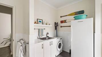 A compact kitchen with a washing machine, a sink, and a refrigerator.
