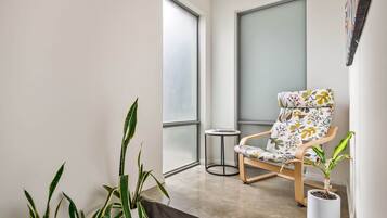 A balcony with a chair, potted plants, and a view through a frosted glass door.