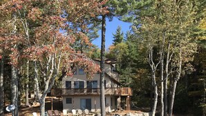 Un chalet au bord du lac, avec un quai, des kayaks et une antenne parabolique.