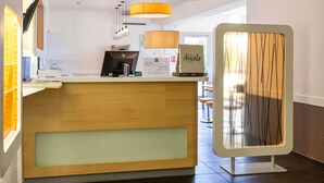 Un espace d’accueil comprenant un comptoir de réception en bois, un ordinateur HP et une lampe.