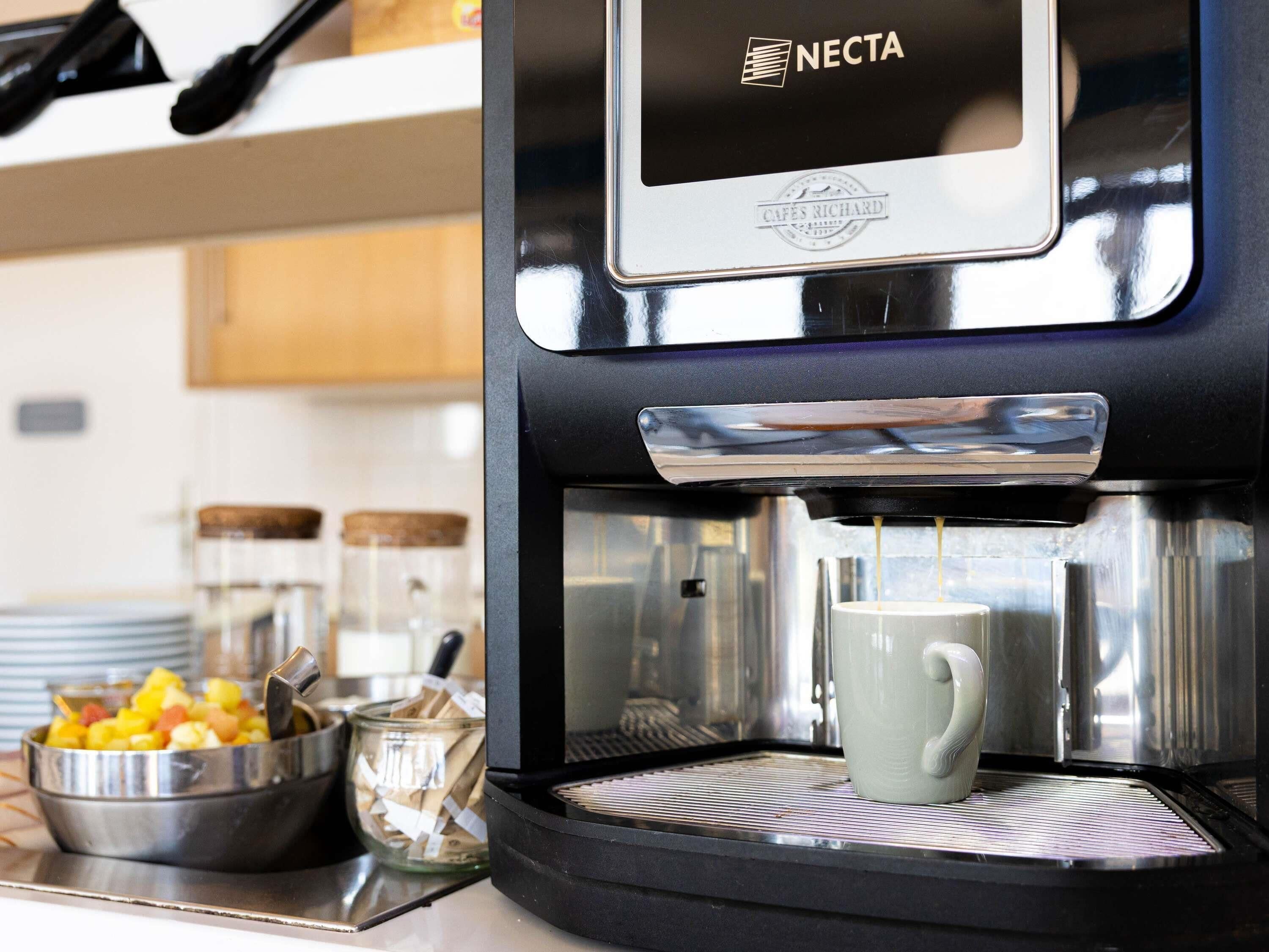 Une machine à café Necta avec une tasse posée sur son bac d’égouttement.