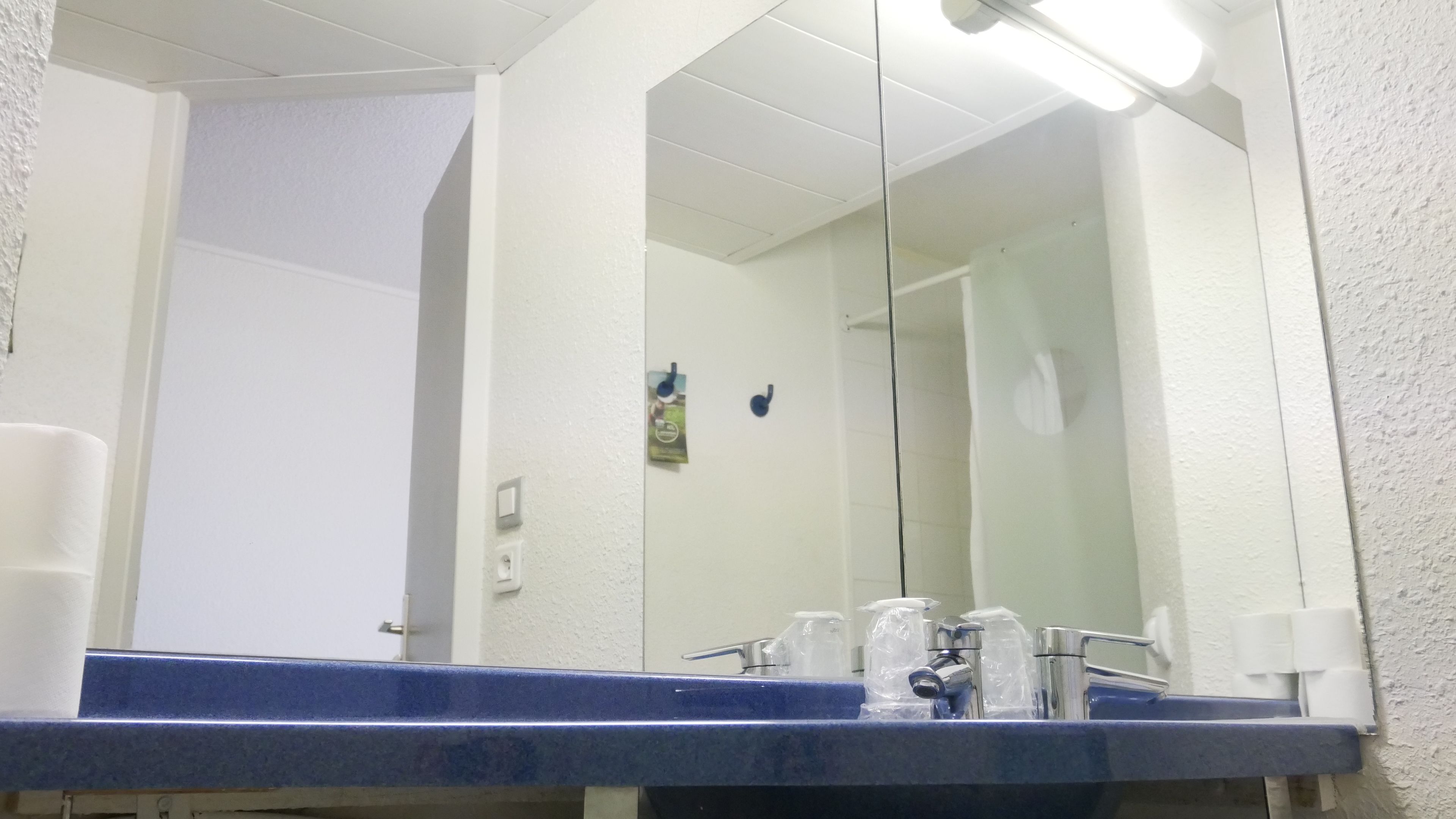 Un baño con un lavamanos azul, un espejo y una puerta blanca.