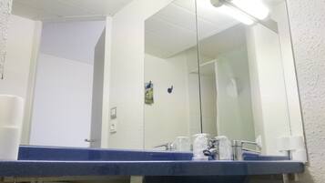 Un baño con un lavamanos azul, un espejo y una puerta blanca.